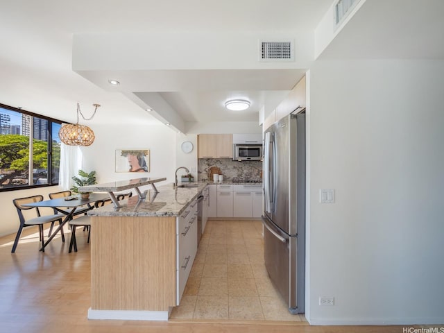 2232 Kapiolani Blvd Unit 303, Honolulu, HI 96826 - kitchen with appliances with stainless steel finishes, a peninsula, light stone countertops, light brown cabinetry, and decorative backsplash