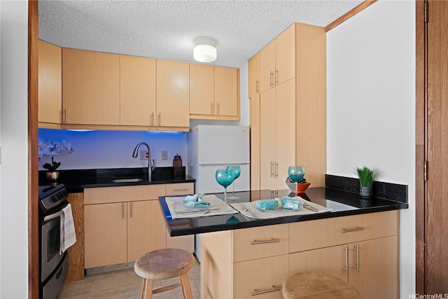 2888 Ala Ilima St Unit 806, Honolulu, HI 96818 - kitchen featuring stainless steel range oven, freestanding refrigerator, light brown cabinets, a peninsula, and dark countertops