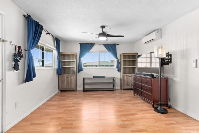 91-1024 Kaiau Ave Unit 4E, Kapolei, HI 96707 - living area with a wall unit AC, a ceiling fan, plenty of natural light, light wood-type flooring, and a textured ceiling