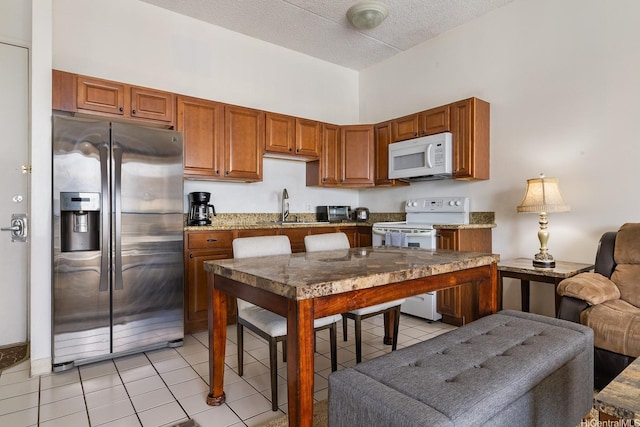 201 Ohua Ave Unit 3702-1, Penthouse Honolulu, HI 96815 - kitchen featuring white appliances, light tile patterned flooring, brown cabinets, open floor plan, and a textured ceiling