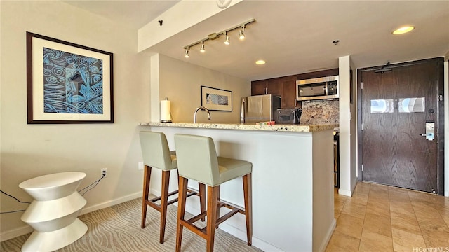 1777 Ala Moana Blvd Unit 2203, Honolulu, HI 96815 - kitchen featuring appliances with stainless steel finishes, a kitchen bar, dark brown cabinetry, a peninsula, and recessed lighting