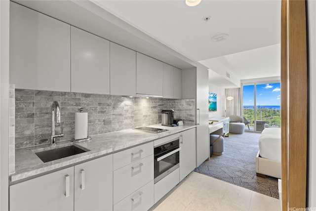 383 Kalaimoku St Unit 1006, Honolulu, HI 96815 - kitchen with oven, decorative backsplash, white cabinetry, modern cabinets, and black electric stovetop