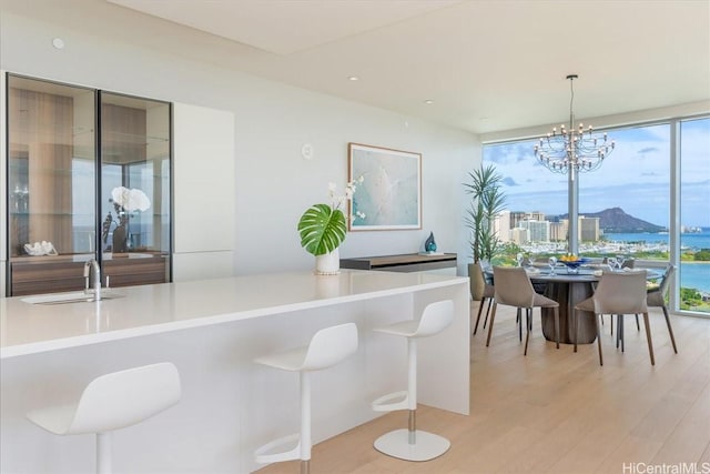 1118 Ala Moana Blvd Unit 2000/2002, Honolulu, HI 96814 - kitchen with light wood-style flooring, light countertops, a breakfast bar, pendant lighting, and floor to ceiling windows