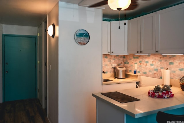 53-549 Kamehameha Hwy Unit 211, Hauula, HI 96717 - kitchen with black electric stovetop, backsplash, a ceiling fan, white cabinets, and a kitchen breakfast bar