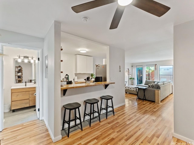 46-63 Emepela Pl Unit P205, Kaneohe, HI 96744 - kitchen featuring a breakfast bar, light wood-style flooring, white cabinetry, freestanding refrigerator, and butcher block countertops