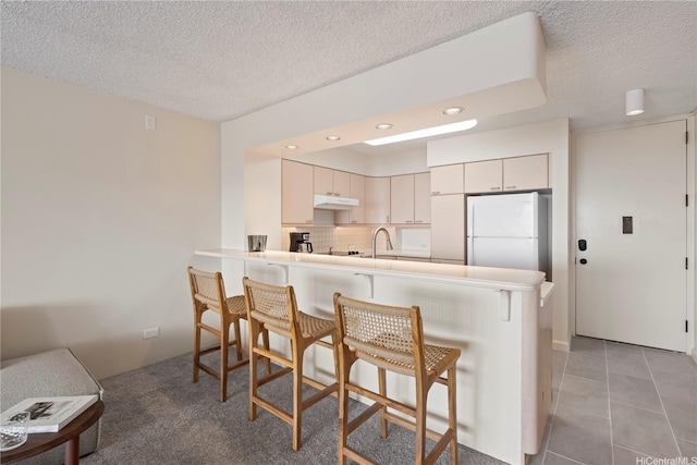 1717 Mott Smith Dr Unit 2811, Honolulu, HI 96822 - kitchen with freestanding refrigerator, under cabinet range hood, a breakfast bar, a peninsula, and a textured ceiling