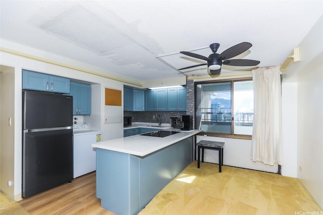 2333 Kapiolani Blvd Unit 608, Honolulu, HI 96826 - kitchen featuring black appliances, washer / dryer, blue cabinetry, a peninsula, and light countertops