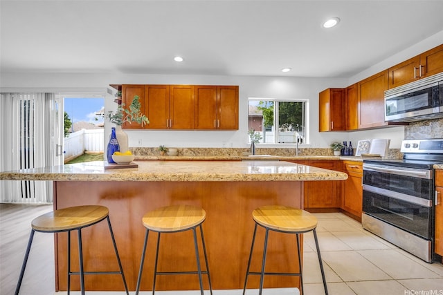 94-1023 Maiau St Unit 172, Waipahu, HI 96797 - kitchen featuring stainless steel appliances, recessed lighting, a kitchen breakfast bar, a kitchen island, and light stone countertops