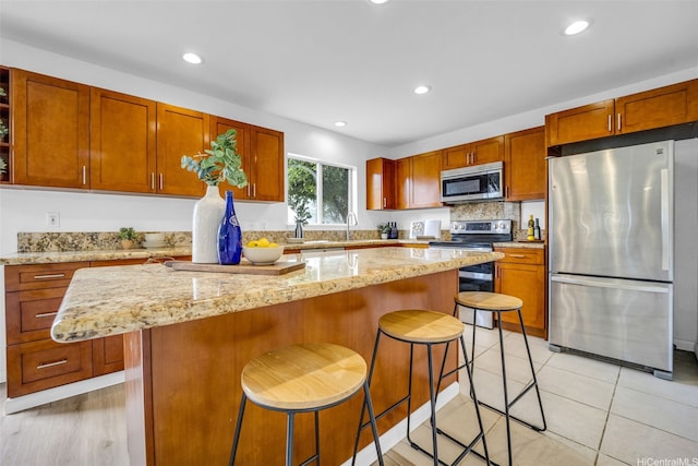 94-1023 Maiau St Unit 172, Waipahu, HI 96797 - kitchen with appliances with stainless steel finishes, a center island, a kitchen bar, recessed lighting, and light stone countertops