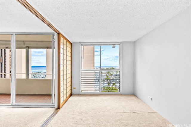 1676 Ala Moana Blvd Unit 1303, Honolulu, HI 96815 - empty room featuring carpet floors, a water view, a textured ceiling, and expansive windows