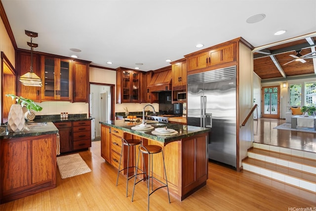1371 Hele St, Kailua, HI 96734 - kitchen featuring appliances with stainless steel finishes, custom exhaust hood, light wood-style flooring, a kitchen island with sink, and recessed lighting