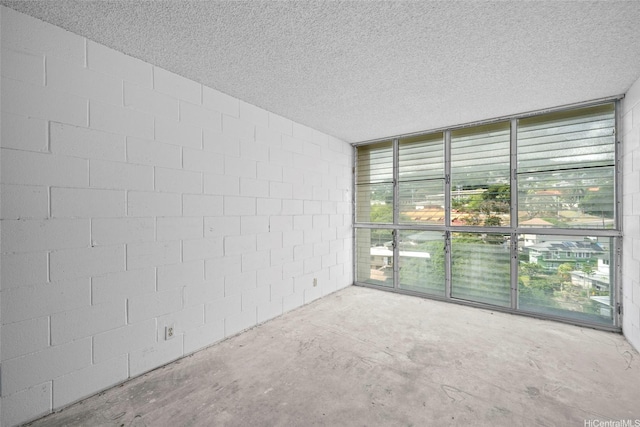 1687 Pensacola St Unit 1004, Honolulu, HI 96822 - unfurnished room featuring concrete block wall, unfinished concrete flooring, floor to ceiling windows, and a textured ceiling