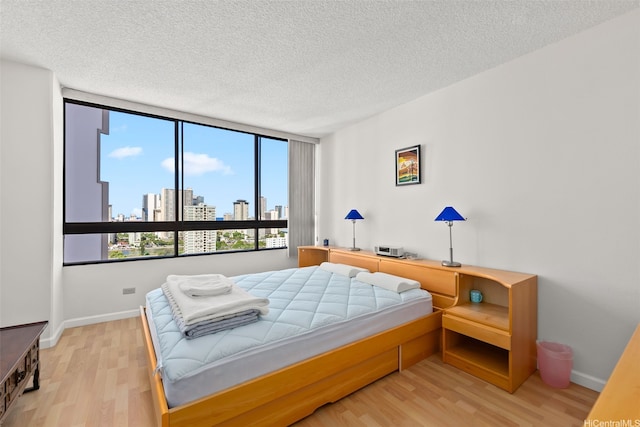 2499 Kapiolani Blvd Unit 2109, Honolulu, HI 96826 - bedroom featuring light wood finished floors, multiple windows, a textured ceiling, and a skyline view