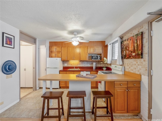 417 Nohonani St Unit 312, Honolulu, HI 96815 - kitchen with white appliances, a peninsula, a breakfast bar area, a textured ceiling, and decorative backsplash