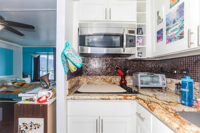 2525 Date St Unit 2303, Honolulu, HI 96826 - kitchen with stainless steel microwave, tasteful backsplash, white cabinetry, ceiling fan, and light stone counters