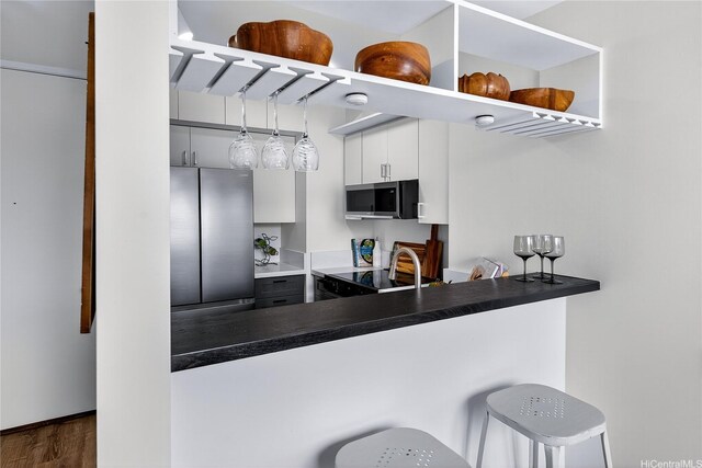 322 Aoloa St Unit 1708, Kailua, HI 96734 - kitchen with stainless steel appliances, dark wood finished floors, a kitchen bar, dark countertops, and a peninsula