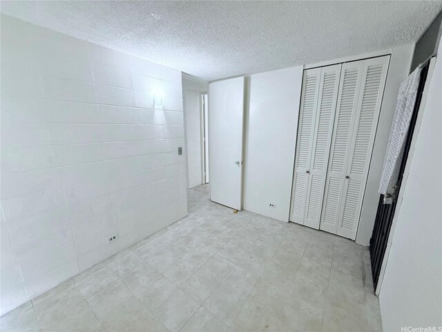 751 Kinau St Unit Dh20, Honolulu, HI 96813 - unfurnished bedroom featuring a textured ceiling, concrete block wall, and a closet