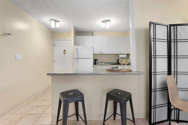 98-1038 Moanalua Rd Unit 1502, Aiea, HI 96701 - kitchen featuring freestanding refrigerator, a peninsula, white cabinets, a kitchen bar, and a textured ceiling
