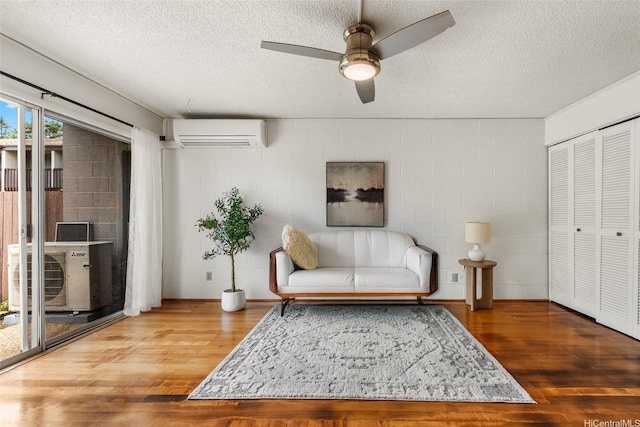 95-45 Hokuiwa St Unit 22, Mililani, HI 96789 - living area featuring a wall mounted AC, a textured ceiling, ceiling fan, wood finished floors, and concrete block wall