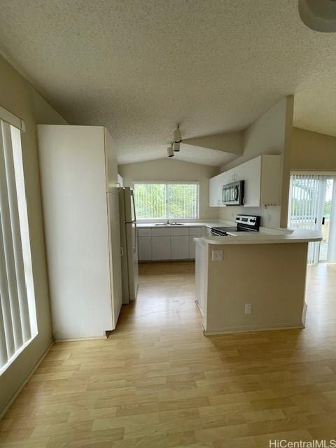 91-1020 Laaulu St Unit 27C, Ewa Beach, HI 96706 - kitchen featuring appliances with stainless steel finishes, a textured ceiling, vaulted ceiling, light wood-style flooring, and a peninsula