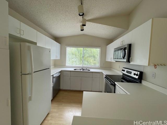 91-1020 Laaulu St Unit 27C, Ewa Beach, HI 96706 - kitchen with stainless steel appliances, vaulted ceiling, light wood-type flooring, a textured ceiling, and light countertops
