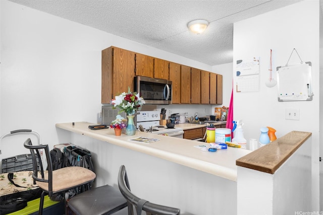 98-402 Koauka Loop Unit 216, Aiea, HI 96701 - kitchen featuring stainless steel microwave, white range with electric stovetop, brown cabinets, light countertops, and a kitchen bar