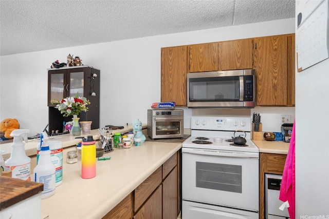 98-402 Koauka Loop Unit 216, Aiea, HI 96701 - kitchen featuring stainless steel microwave, electric stove, brown cabinetry, light countertops, and a textured ceiling