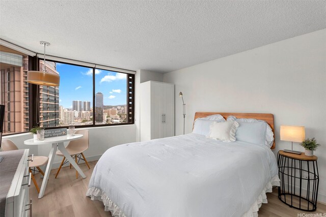 444 Niu St Unit 2403, Honolulu, HI 96815 - bedroom with wood finished floors, a textured ceiling, and a view of city