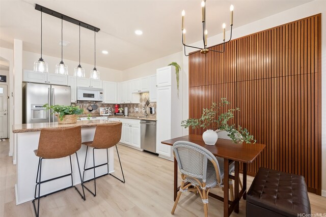 91-1021 Kaileolea Dr Unit H3, Ewa Beach, HI 96706 - kitchen featuring appliances with stainless steel finishes, decorative backsplash, a center island, white cabinetry, and light wood-style floors
