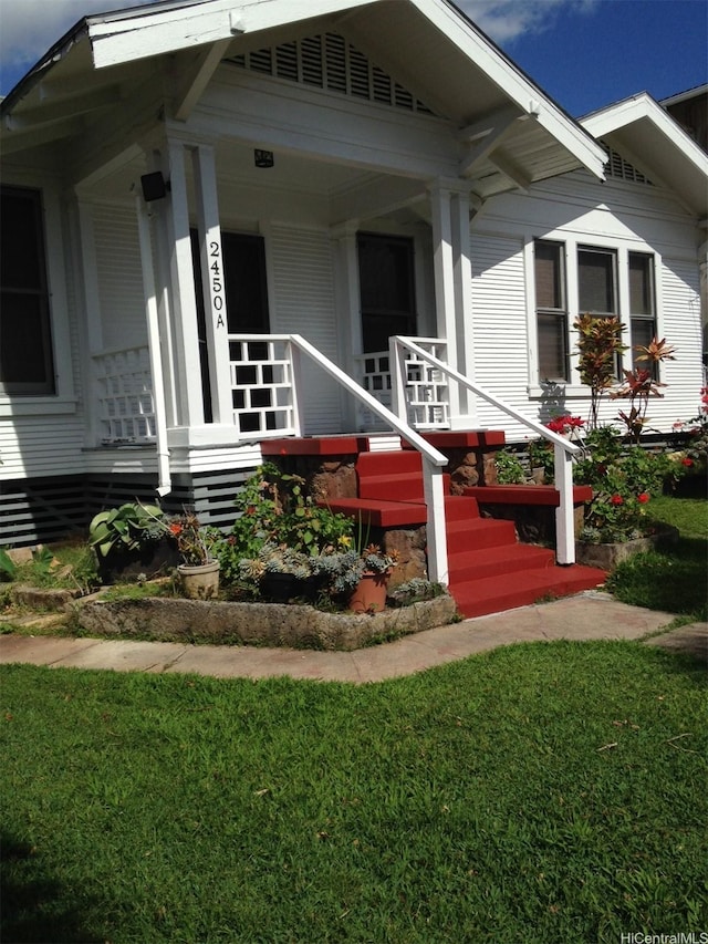 entrance to property featuring a porch and a lawn