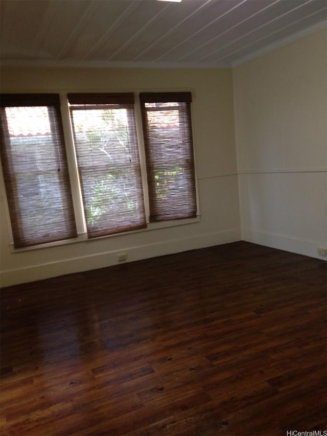 spare room featuring dark wood-style floors and baseboards