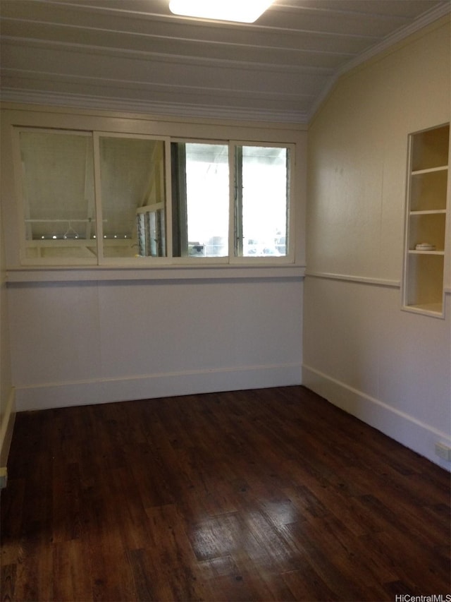 empty room with crown molding, wood finished floors, and vaulted ceiling