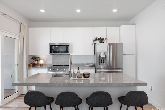 91-1641 Honouliuli St Unit 42, Ewa Beach, HI 96706 - kitchen with stainless steel appliances, a breakfast bar, white cabinets, light wood finished floors, and recessed lighting