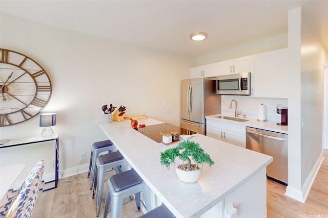 84-687 Ala Mahiku St Unit 120B, Waianae, HI 96792 - kitchen with stainless steel appliances, a breakfast bar area, white cabinetry, light wood-style flooring, and a peninsula