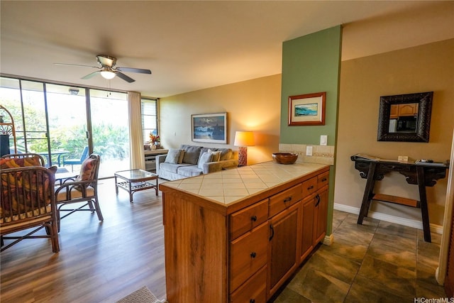 57-101 Kuilima Dr Unit 189, Kahuku, HI 96731 - kitchen featuring tile counters, a ceiling fan, open floor plan, brown cabinets, and a wall of windows