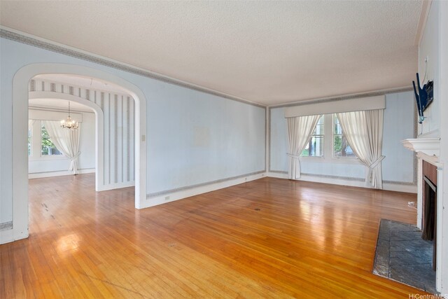 1186 Alewa Dr, Honolulu, HI 96817 - unfurnished living room with arched walkways, a textured ceiling, a chandelier, wood-type flooring, and healthy amount of natural light