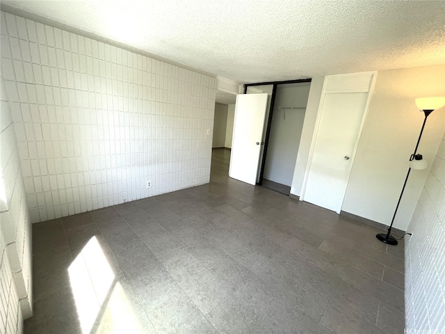1720 Huna St Unit B102, Honolulu, HI 96817 - unfurnished bedroom featuring tile walls, a textured ceiling, and two closets