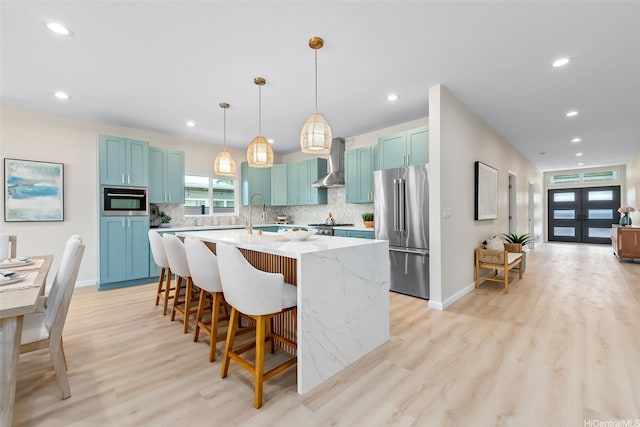 1076 Kahili St, Kailua, HI 96734 - kitchen with stainless steel fridge, wall chimney exhaust hood, blue cabinetry, tasteful backsplash, and recessed lighting