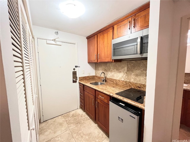 1700 Ala Moana Blvd Unit 1702, Honolulu, HI 96815 - kitchen featuring stainless steel microwave, black electric stovetop, decorative backsplash, brown cabinets, and light stone countertops