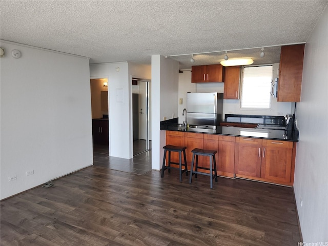 98-099 Uao Pl Unit Ph5, Aiea, HI 96701 - kitchen with stainless steel appliances, dark countertops, dark wood finished floors, track lighting, and a textured ceiling
