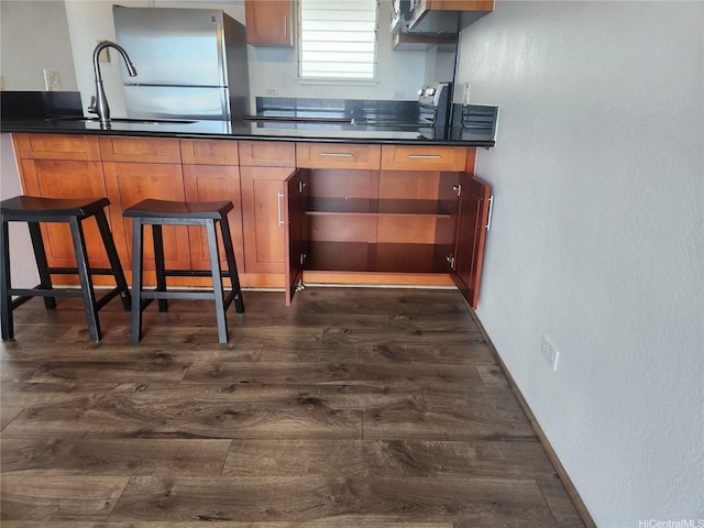 98-099 Uao Pl Unit Ph5, Aiea, HI 96701 - kitchen featuring stainless steel appliances, dark wood-style flooring, dark countertops, a textured wall, and brown cabinetry