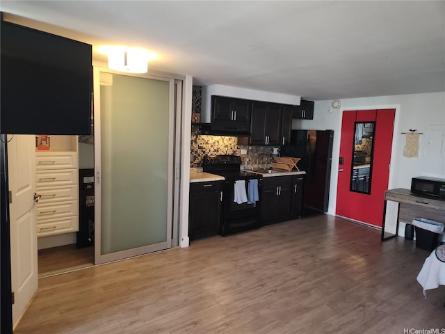 824 Kinau St Unit 403, Honolulu, HI 96813 - kitchen with black appliances, dark cabinets, light countertops, backsplash, and light wood-style flooring