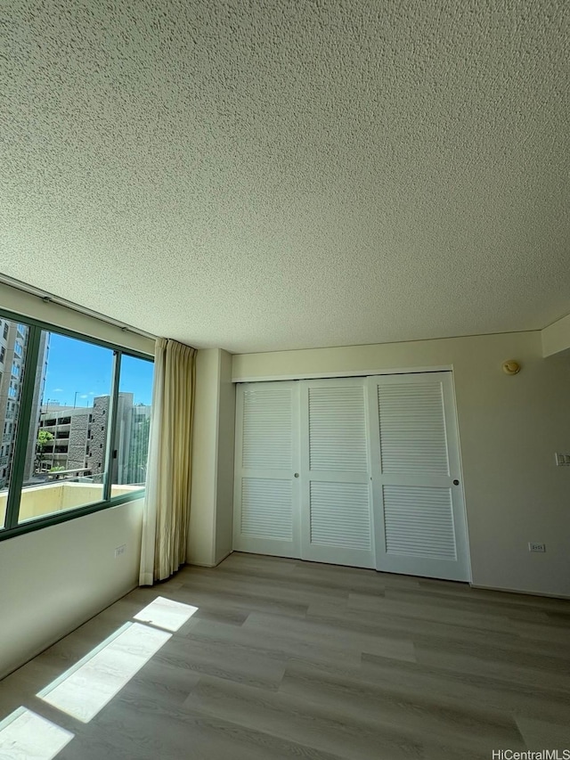 1314 Kalakaua Ave Unit 304, Honolulu, HI 96826 - unfurnished bedroom featuring a textured ceiling, light wood finished floors, and a closet