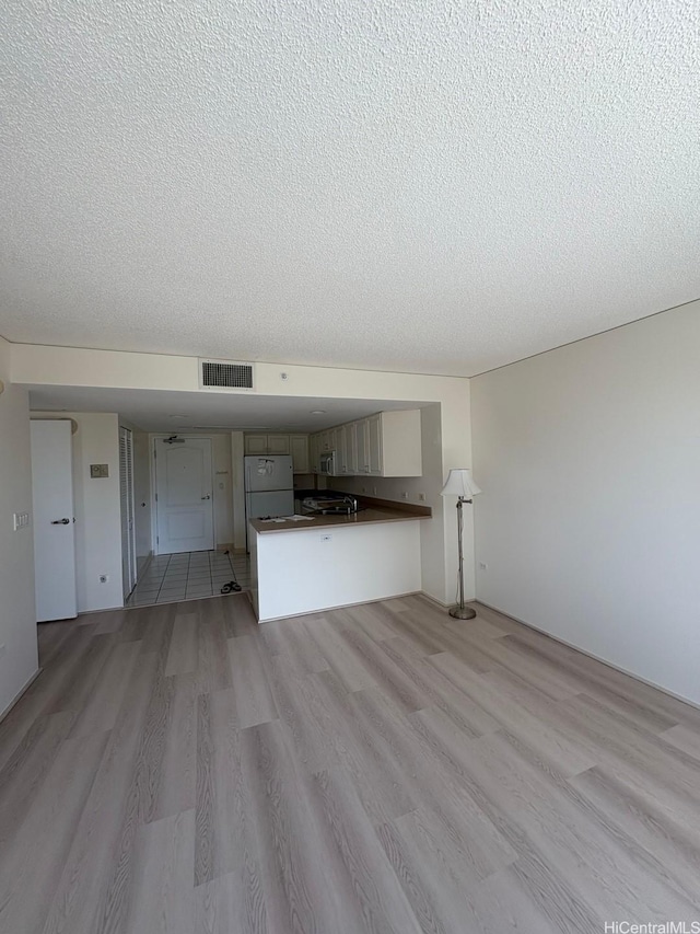 1314 Kalakaua Ave Unit 304, Honolulu, HI 96826 - unfurnished living room featuring light wood-type flooring and a textured ceiling