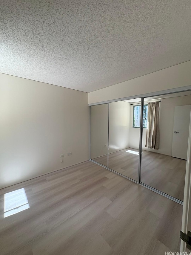 1314 Kalakaua Ave Unit 304, Honolulu, HI 96826 - unfurnished bedroom featuring light wood-style flooring, a textured ceiling, and a closet