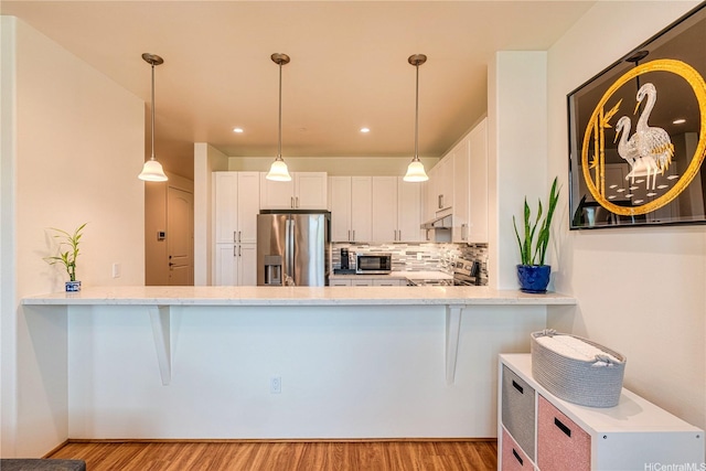 94-1188 Kalahikiola Dr Unit 1005, Waipahu, HI 96797 - kitchen featuring stainless steel appliances, light wood finished floors, under cabinet range hood, white cabinets, and a peninsula
