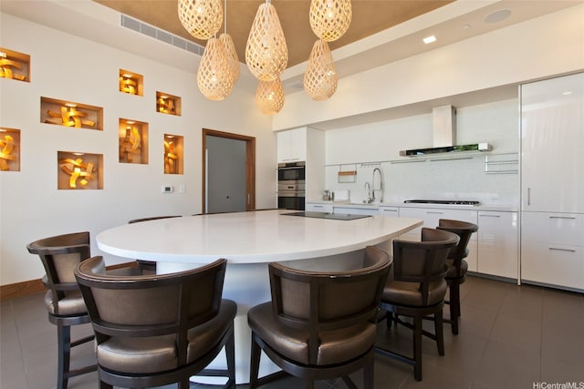 1555 Kapiolani Blvd Unit 1205, Honolulu, HI 96814 - kitchen with wall chimney exhaust hood, dark tile patterned floors, white cabinets, tasteful backsplash, and a kitchen breakfast bar