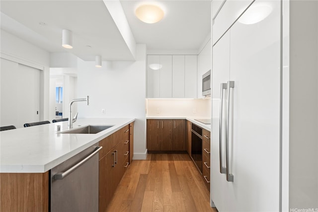 629 Keeaumoku St Unit 2212, Honolulu, HI 96814 - kitchen with built in appliances, a peninsula, light wood-type flooring, and light countertops