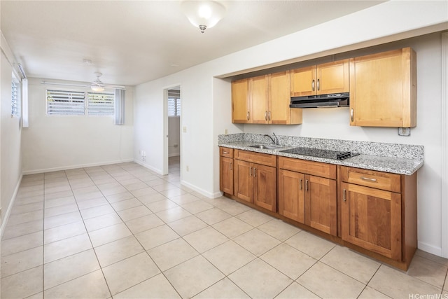 4134 Likini St, Honolulu, HI 96818 - kitchen with black electric stovetop, under cabinet range hood, light stone countertops, and light tile patterned floors