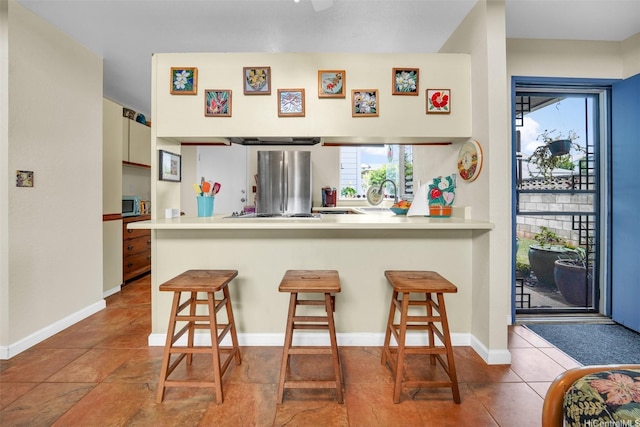 94-517 Poloahilani St, Mililani, HI 96789 - kitchen featuring freestanding refrigerator, a breakfast bar, a peninsula, and tile patterned floors